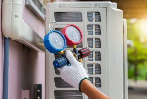 Repairman holding gauges while fixing air conditioning system
